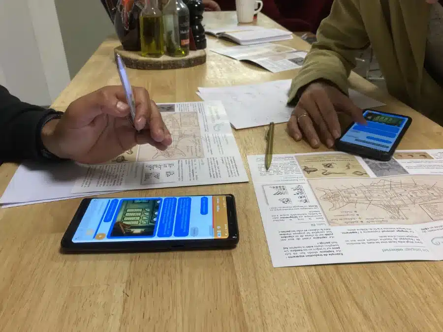 Documents d'enquête, carte et smartphone sur une table pendant un escape game hybride en entreprise